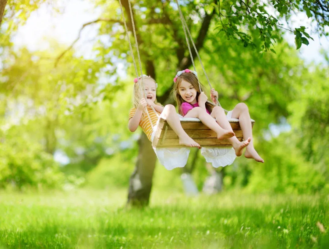 Two girls playing on a swing.